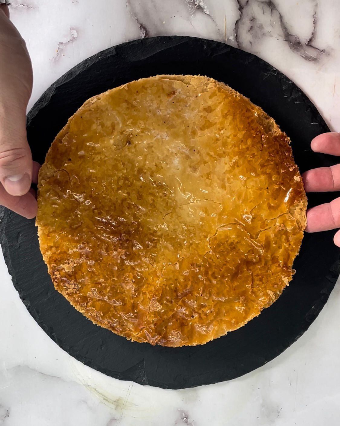 Una persona tiene in mano una tortilla su un piatto nero.