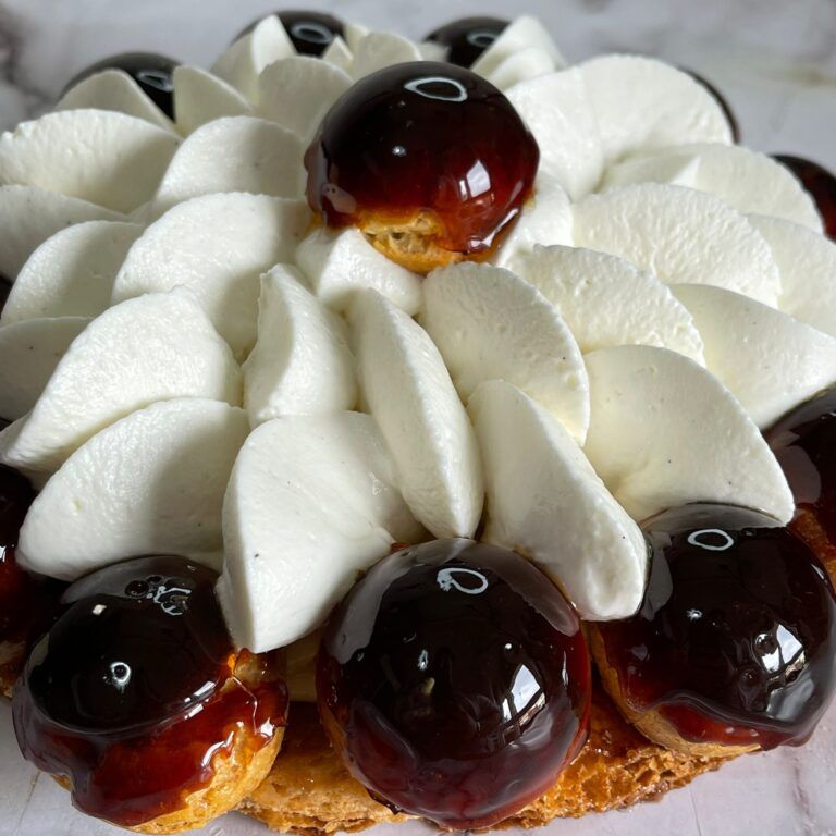 Un primo piano di una torta con panna montata e ciliegie sopra