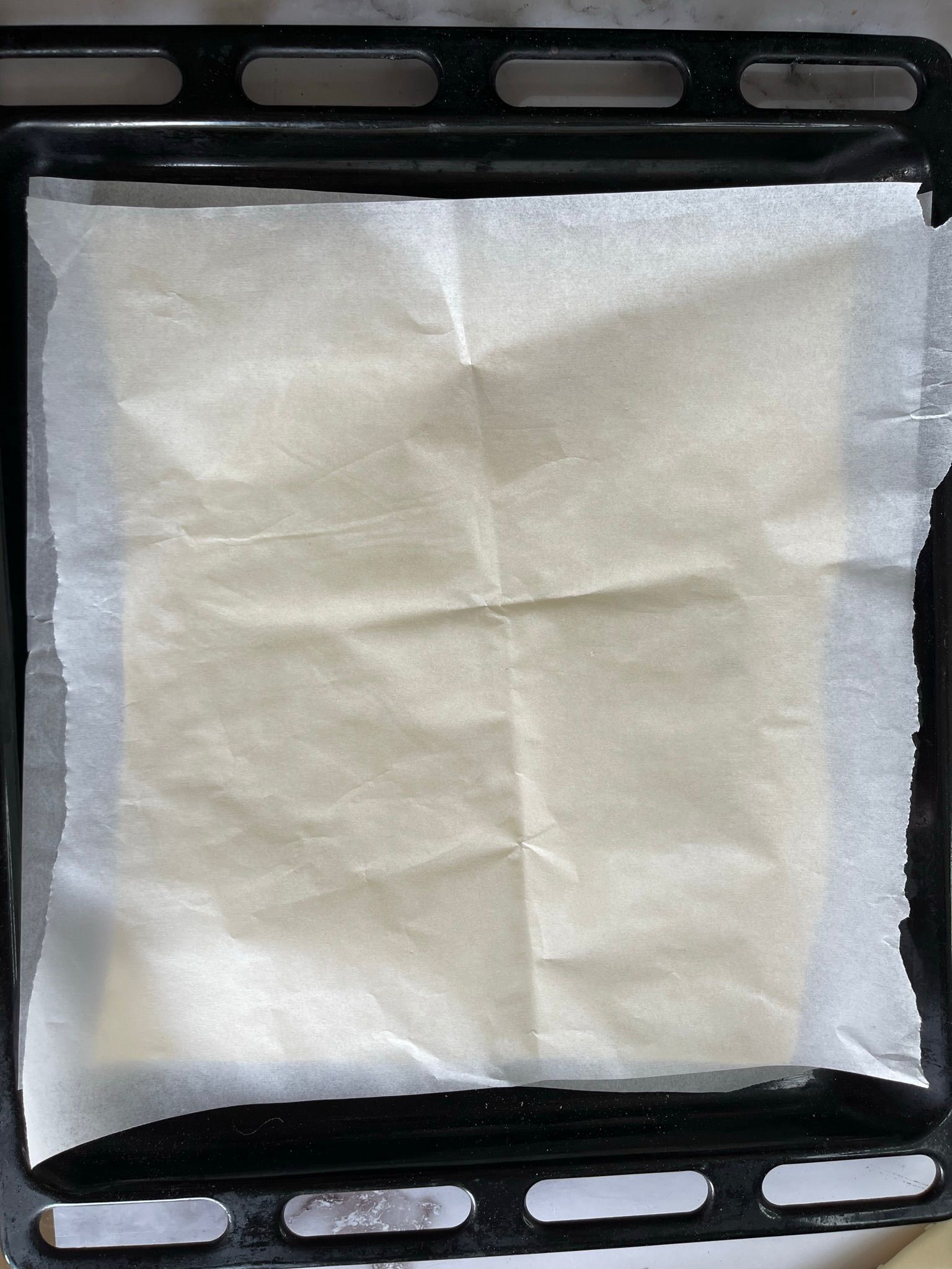 Un pezzo di carta oleata è appoggiato su una teglia da forno.