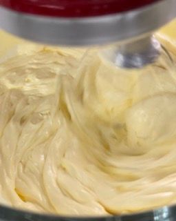 Primo piano di un mixer che prepara la panna montata in una ciotola.