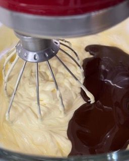 Un mixer mescola uova e cioccolato in una ciotola di vetro.