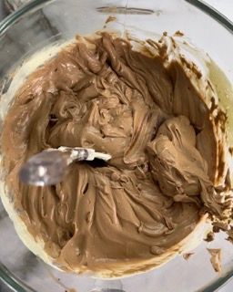 Una ciotola di glassa al cioccolato con un cucchiaio dentro.
