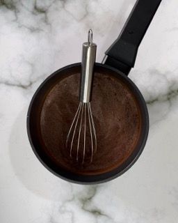 Una frusta è in una pentola di salsa al cioccolato.
