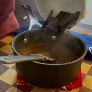 Una persona sta versando del cioccolato in una pentola di zuppa