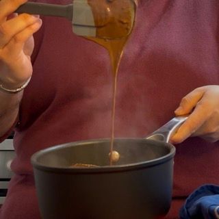 Una persona che versa del liquido in una pentola con una spatola