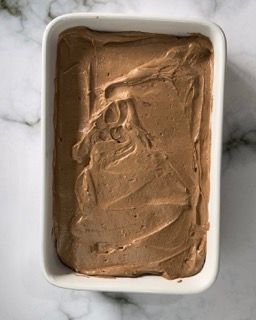 Una ciotola bianca piena di gelato al cioccolato su un tavolo.