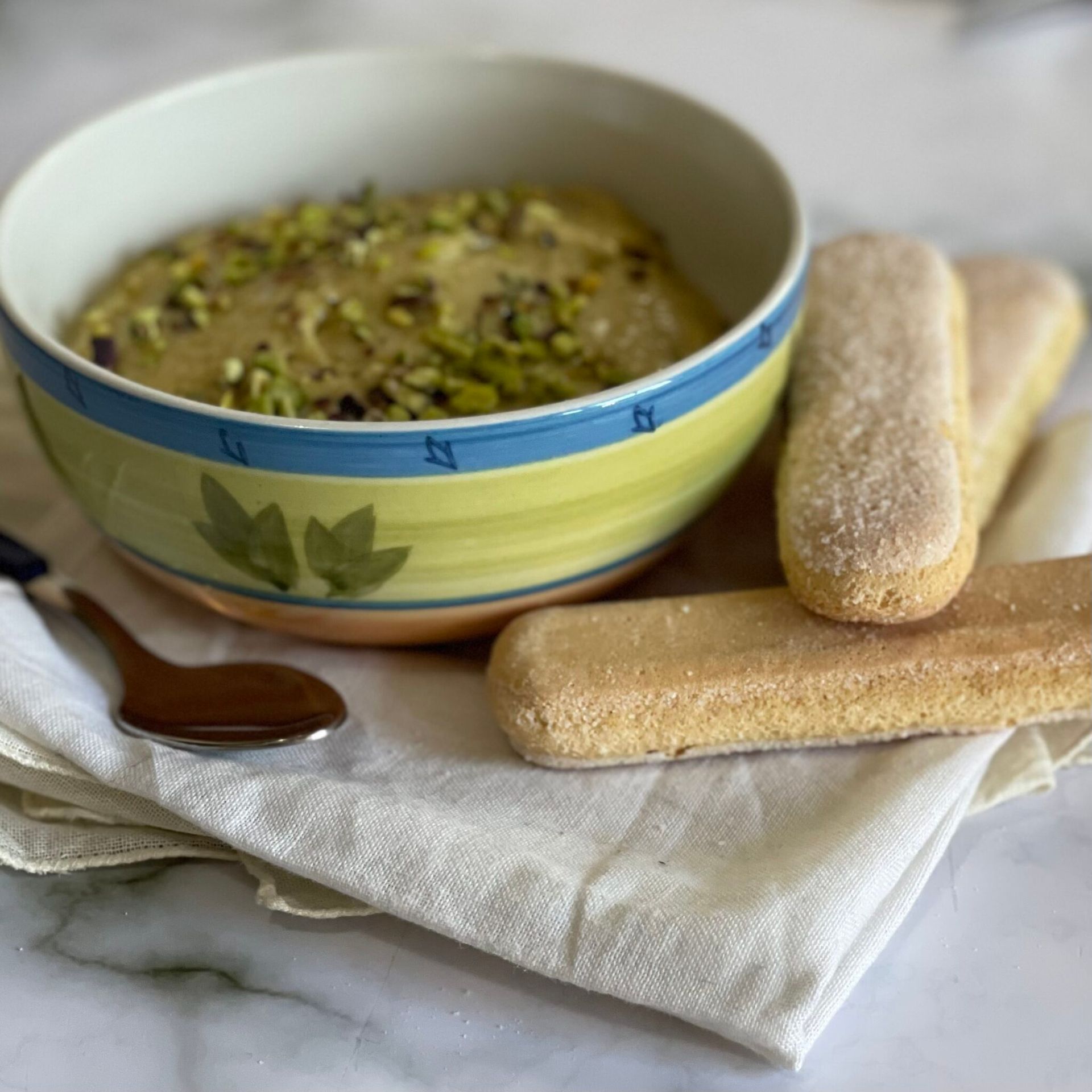 Una ciotola di cibo accanto a un cucchiaio e alcuni biscotti