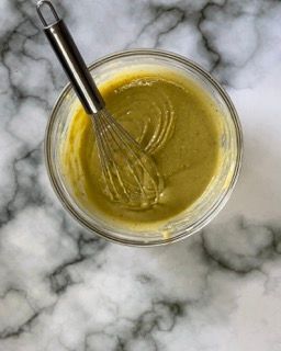 Una ciotola di salsa verde con una frusta dentro.