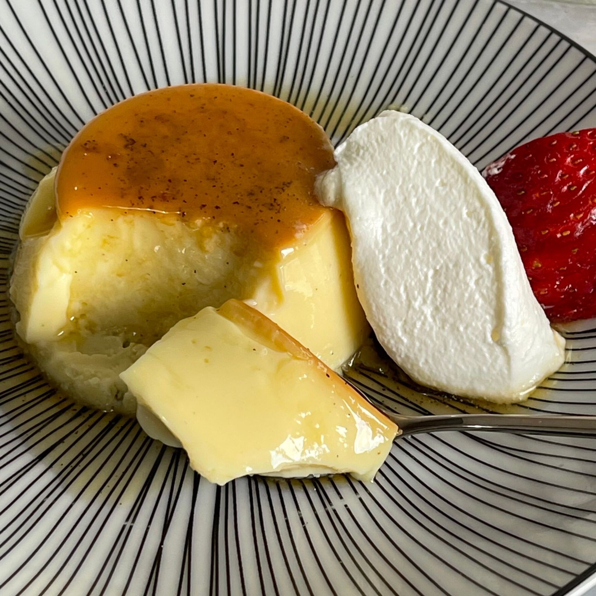 Un primo piano di un dessert con panna montata e fragole su un piatto.