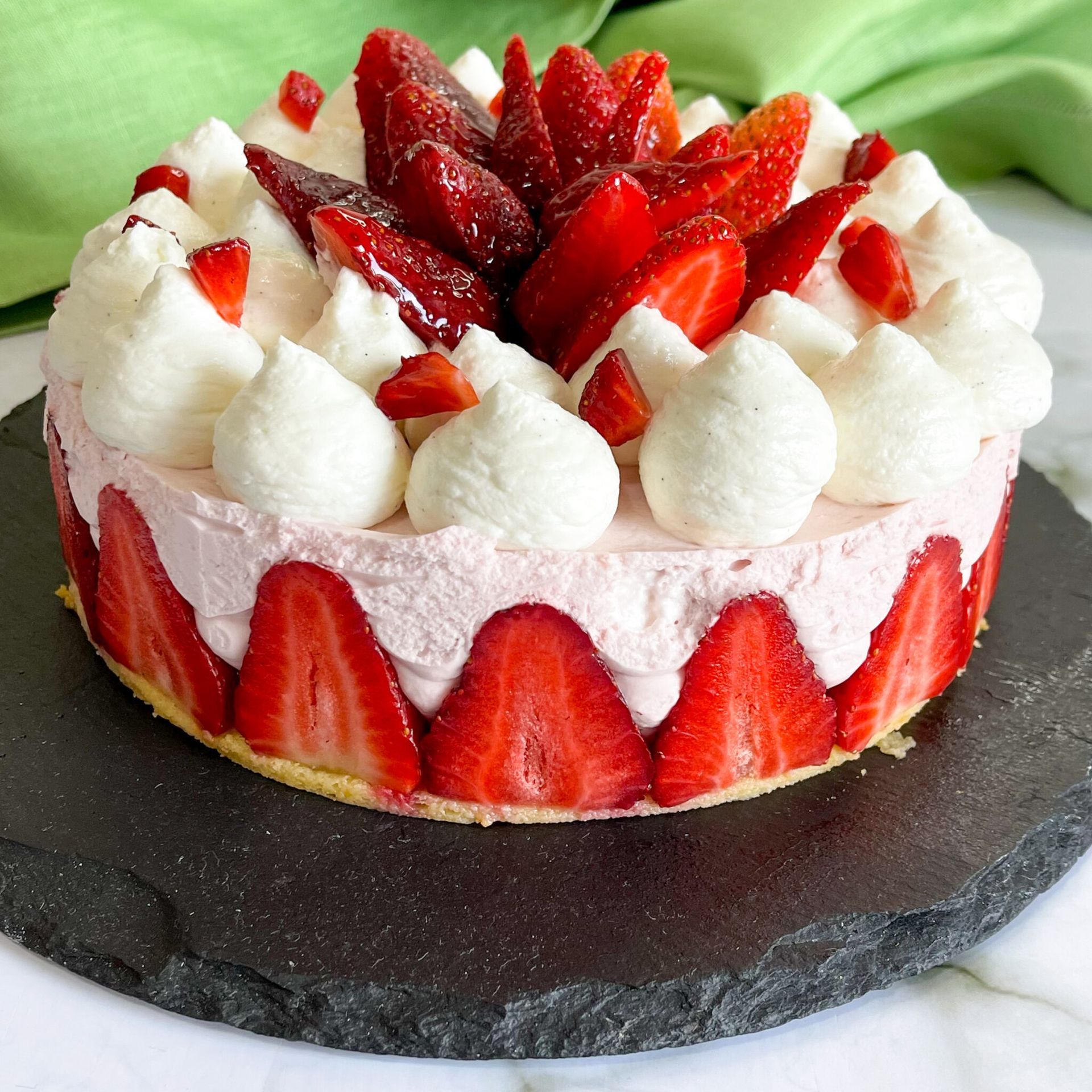 Una torta con fragole e panna montata sopra