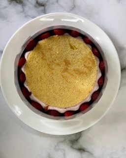 Un piatto bianco sormontato da una torta e delle fragole