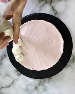 Una persona sta glassando una torta con glassa rosa