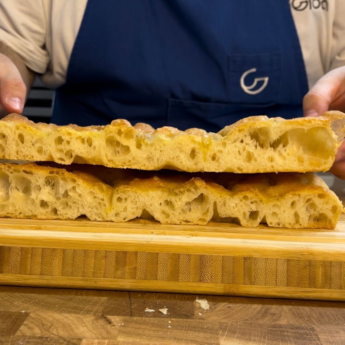 Fetta di focaccia alta e soffice servita tiepida, mostra l'alveolatura
