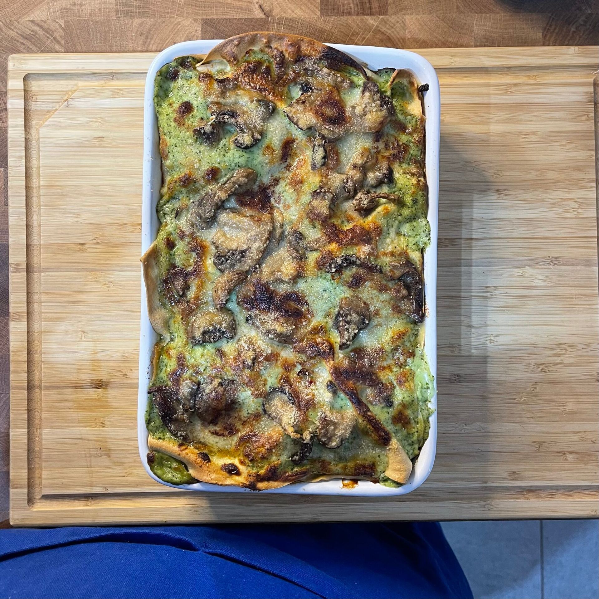 Una casseruola piena di cibo è appoggiata su un tagliere di legno.