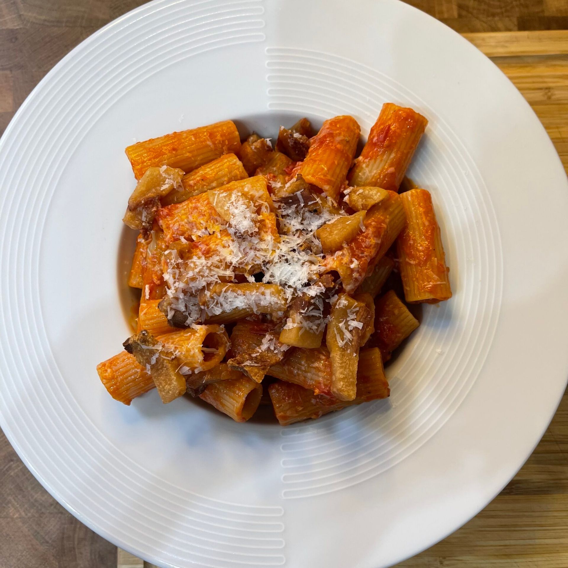 Un piatto bianco con sopra pasta e salsa su un tavolo di legno