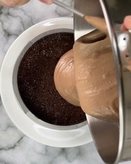 Una persona sta versando la glassa al cioccolato in una tortiera.