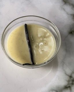 Una ciotola di salsa alla vaniglia con una bacca di vaniglia dentro.