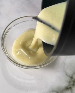 Un primo piano di una ciotola di salsa che viene versata al suo interno.