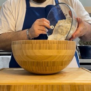 Un uomo sta versando qualcosa in una ciotola di legno