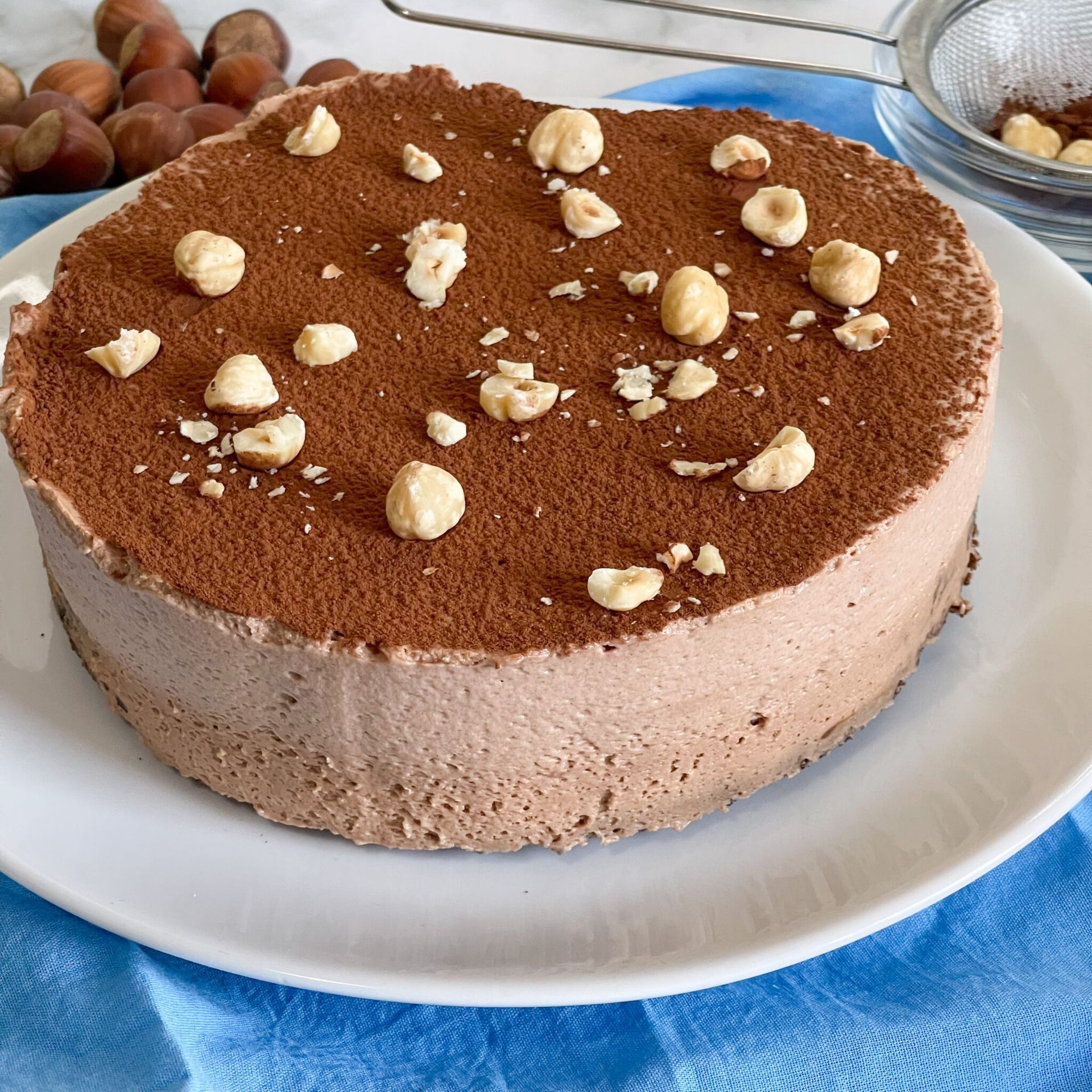 Una torta al cioccolato con sopra delle noci è su un piatto bianco