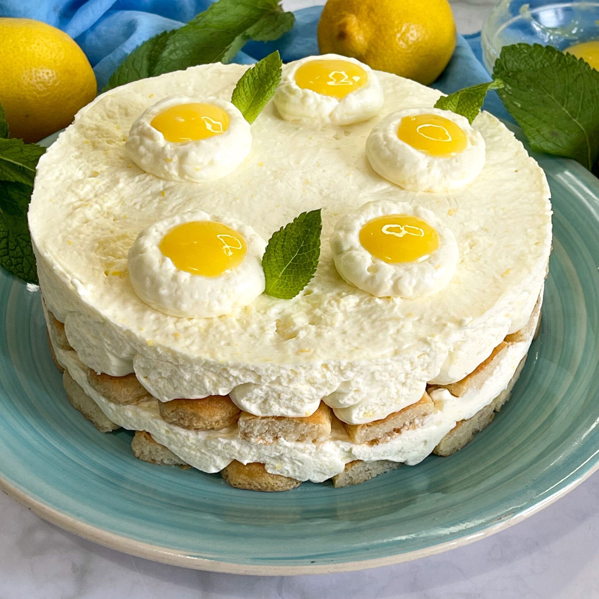 Una torta su un piatto blu con limoni sullo sfondo