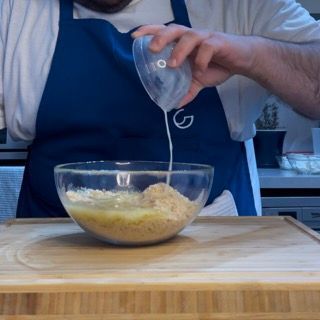Una persona che versa del liquido in una ciotola di cibo