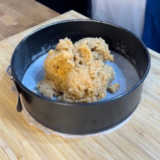 Un colino pieno di impasto è appoggiato su un tavolo di legno