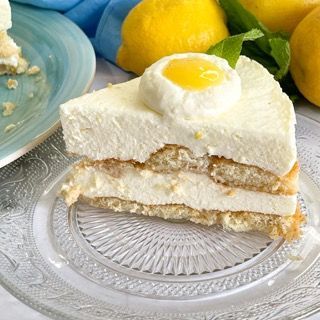Una fetta di torta su un piatto di vetro con limoni sullo sfondo