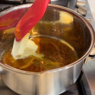 Una pentola di burro viene mescolata con una spatola rossa