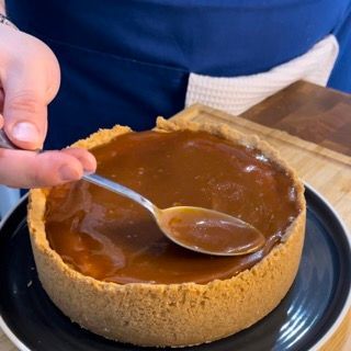 Una persona sta immergendo una torta nella salsa al caramello con un cucchiaio