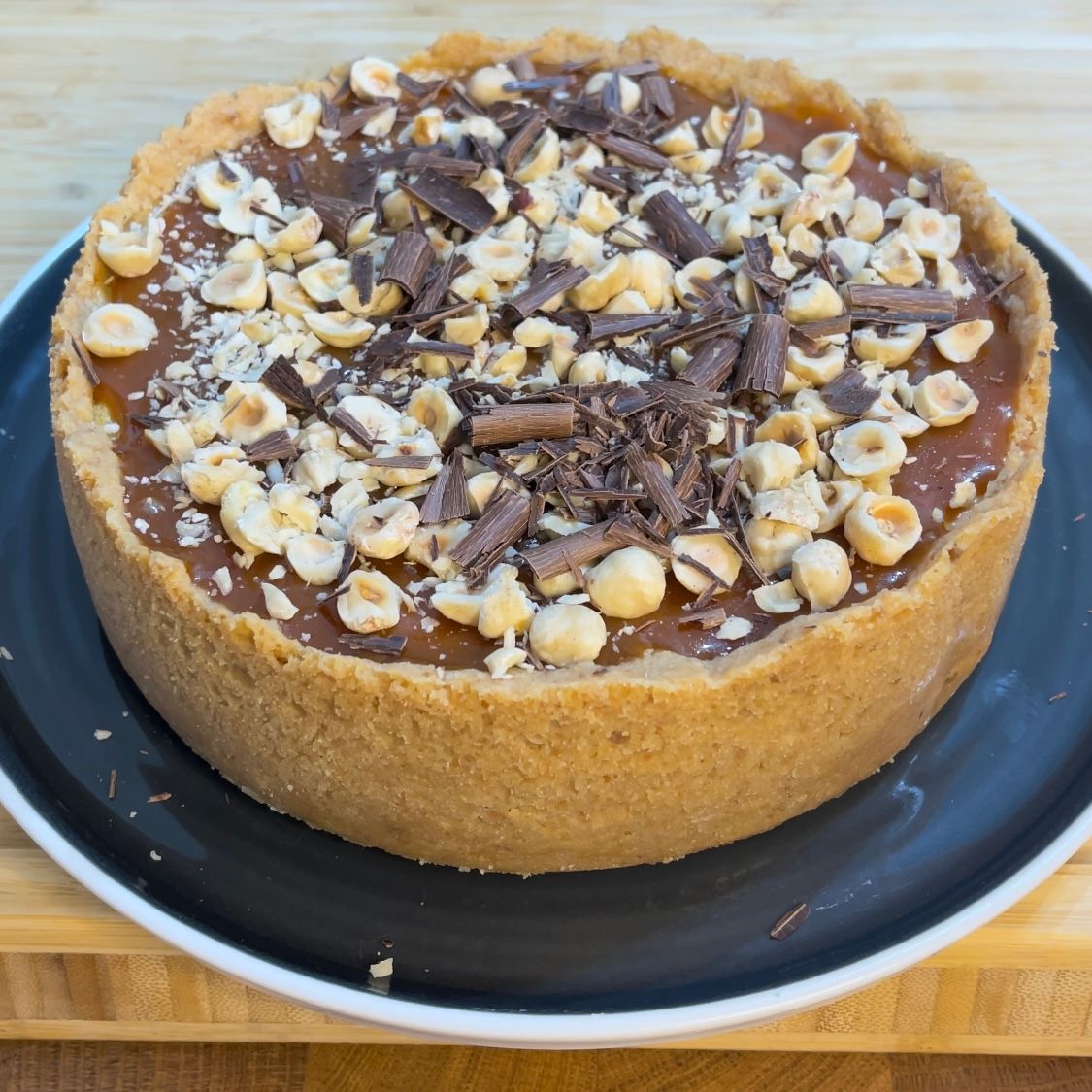 Una torta al cioccolato con sopra delle noci è su un piatto nero