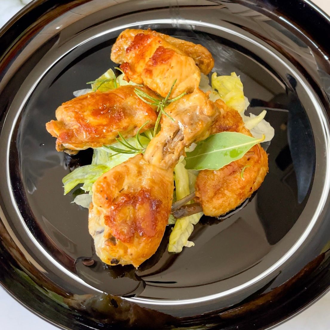 Un piatto nero condito con pollo fritto e lattuga