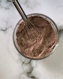 Una ciotola di cioccolato in polvere con una frusta dentro.