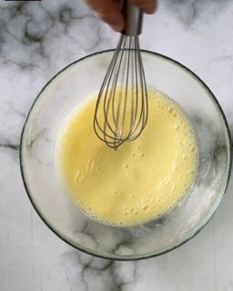 Una persona sta mescolando un liquido giallo in una ciotola di vetro.