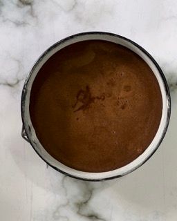 Una ciotola di liquido marrone su una superficie di marmo