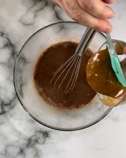 Una persona versa la salsa in una ciotola con una frusta.