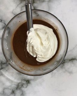 Una ciotola di cioccolato e panna montata con una frusta dentro.