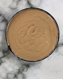 Una ciotola piena di liquido marrone è appoggiata su una superficie di marmo.