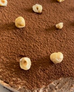 Un primo piano di una torta al cioccolato con nocciole sopra.
