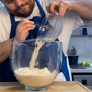 Mix di liquidi e lievito versato sulla farina in planetaria