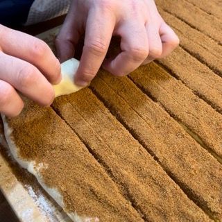 Una singola striscia di impasto e cannella pronta per essere arrotolata