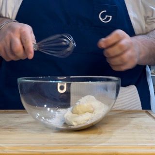 Formaggio spalmabile, burro e sciroppo d'acero in una ciotola, Zucchero a velo setacciato sul composto per la glassa