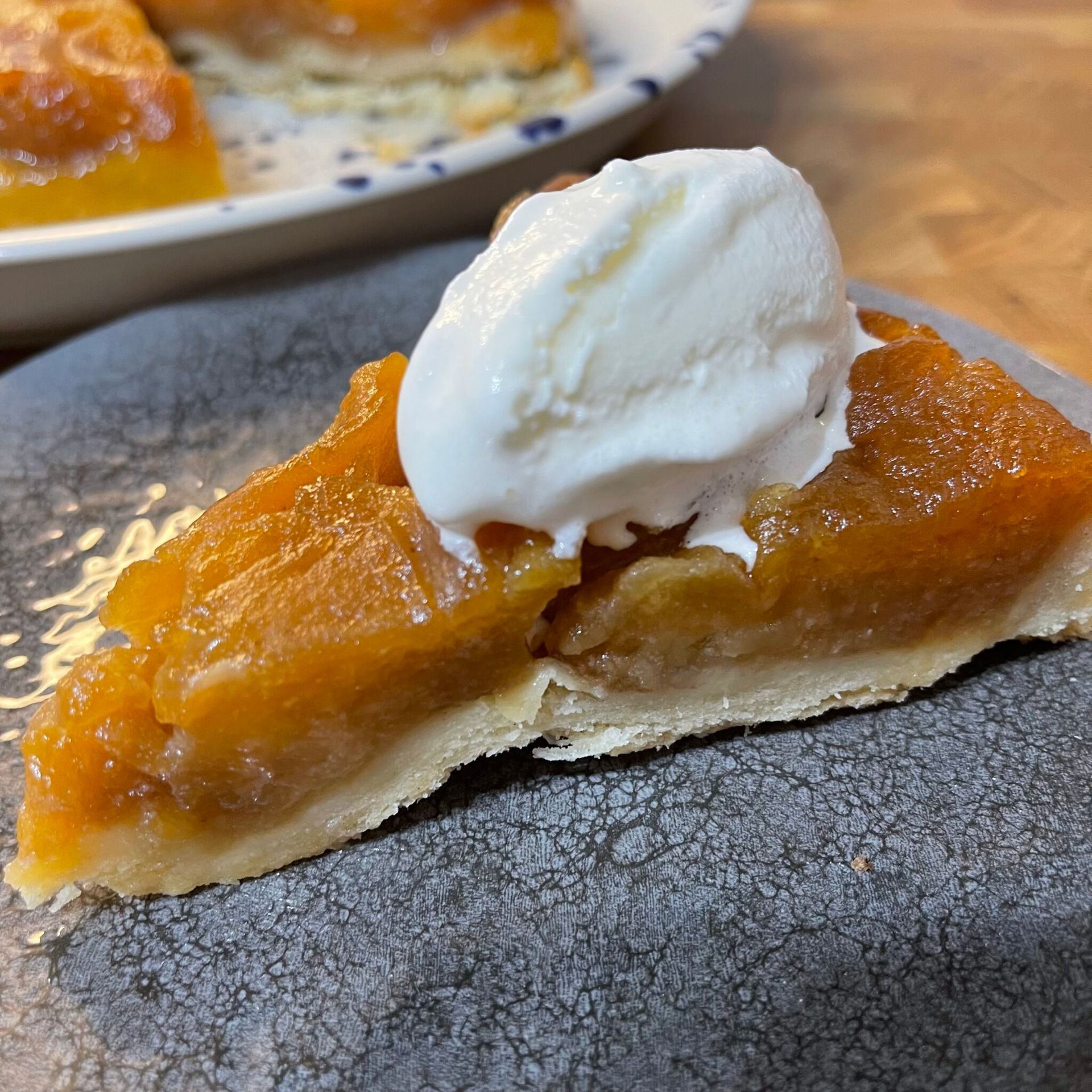 Una fetta di torta di mele con panna montata sopra su un piatto.