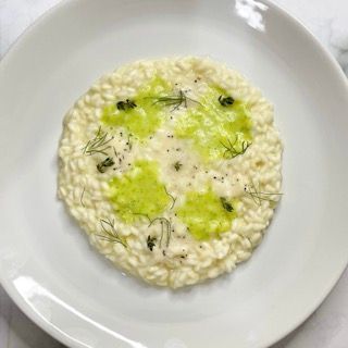 Un piatto bianco sormontato da un cerchio di riso e salsa verde.