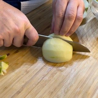Una persona sta tagliando una mela su un tagliere