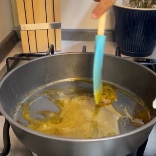 Una persona sta mescolando una pentola di liquido con un cucchiaio blu