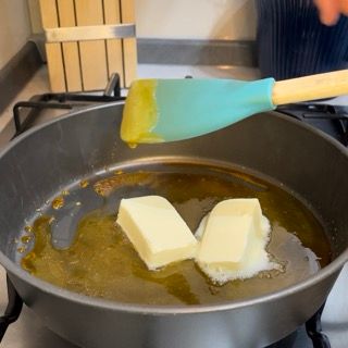 Due pezzetti di burro vengono mescolati in una padella con una spatola