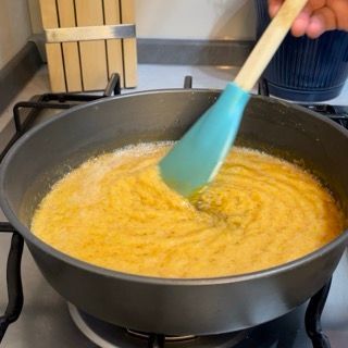Una persona sta mescolando una pentola di cibo con un cucchiaio blu