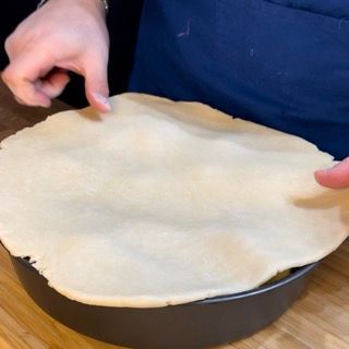 Una persona tiene in mano una crosta di torta in una padella