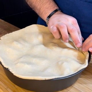 Una persona tiene in mano un pezzo di pasta per torta